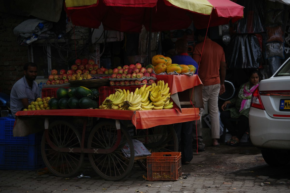 A market cart of fruit with customers alongside